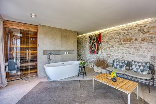 a bathroom with a tub and a couch and a table at Villa Batalini in Šumber