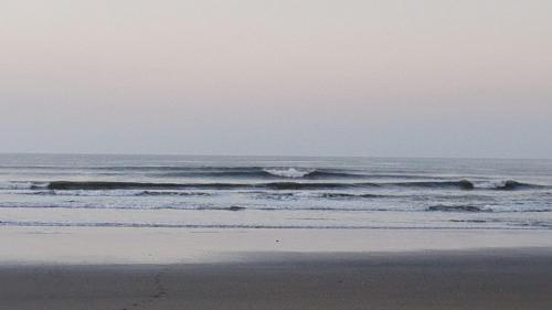 a person standing on a beach with waves in the ocean at Bongo Experience in Jucuarán