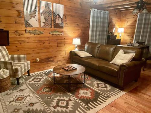 a living room with a leather couch and a table at Clover Creek Cabin in Waynesville