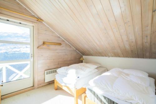 two beds in a room with a window at Les Chalets de Flaine Hameau - maeva Home - Chalet Pièces - Sélection 56 in Flaine