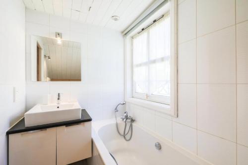 La salle de bains est pourvue d'un lavabo, d'une baignoire et d'un miroir. dans l'établissement Les Chalets de Flaine Hameau - maeva Home - Chalet Pièces - Sélection 56, à Flaine