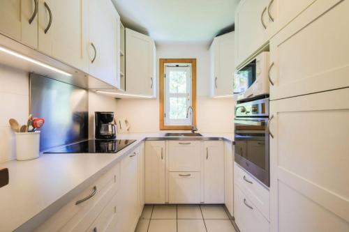 une cuisine blanche avec des armoires blanches et une fenêtre dans l'établissement Les Chalets de Flaine Hameau - maeva Home - Chalet 4 Pièces 8 Personnes - Confort MAE-3660, à Flaine