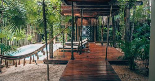 a wooden walkway in a resort with benches and palm trees at Orchid House Tulum Jungle in Tulum