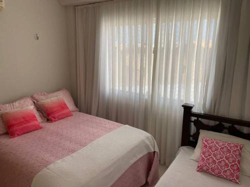 Schlafzimmer mit einem Bett in rosa und weiß in der Unterkunft Condomínio na praia em Nísia Floresta - Tabatinga - Natal/RN in Nísia Floresta