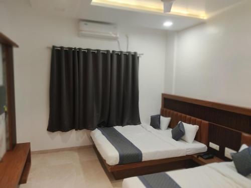 um quarto com 2 camas e uma cortina preta em Hotel Nandan em Shegaon