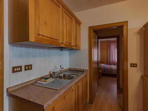 uma cozinha com armários de madeira e um lavatório em Residenza 3-Tre em Madonna di Campiglio