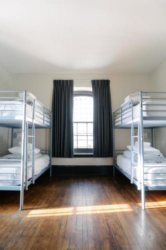 two bunk beds in a room with a window at Saintlo Ottawa Jail Hostel in Ottawa