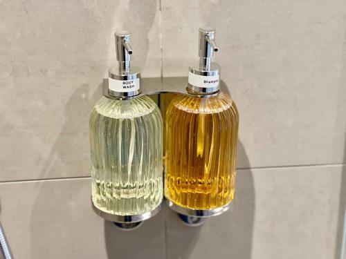 zwei Flaschen gelber Seife an der Wand hängen in der Unterkunft Luxury King-bed Ensuite With Quiet Private Patio in London