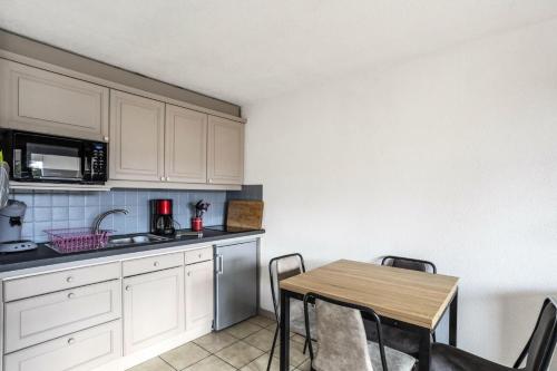 une cuisine avec des armoires blanches et une table avec des chaises dans l'établissement Résidence Arche - maeva Home - Studio 4 Personnes - Confort MAE-3692, à Arâches-la-Frasse