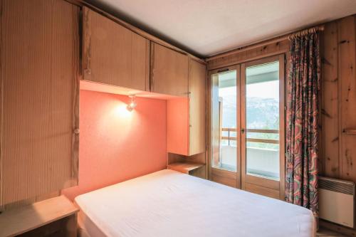 een slaapkamer met een bed en een raam bij Résidence Arche - maeva Home - Appartement 2 Pièces 6 Personnes - Confort 96 in Arâches-la-Frasse