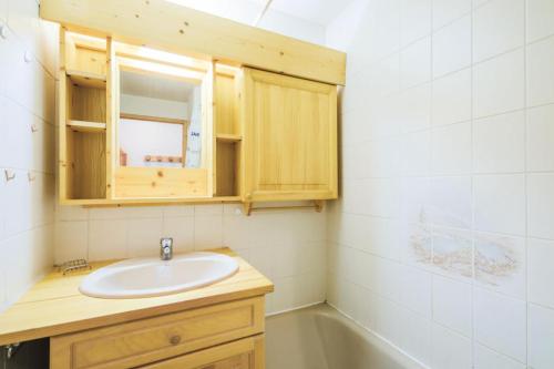 een badkamer met een wastafel, een spiegel en een bad bij Résidence Arche - maeva Home - Appartement 2 Pièces 6 Personnes - Confort 96 in Arâches-la-Frasse