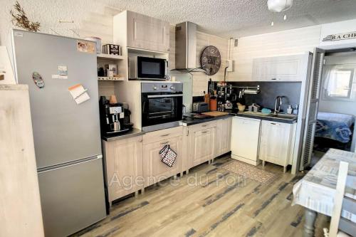 une cuisine avec des armoires en bois et un réfrigérateur dans l'établissement Appartement sur la marina, à Saint Cyprien Plage