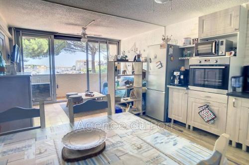 une cuisine avec des appareils blancs et une grande fenêtre dans l'établissement Appartement sur la marina, à Saint Cyprien Plage