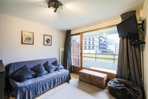 un salon avec un canapé bleu et une grande fenêtre dans l'établissement Résidence Arche - maeva Home - Appartement 2 Pièces 4 Personnes - Sélection MAE-3699, à Arâches-la-Frasse