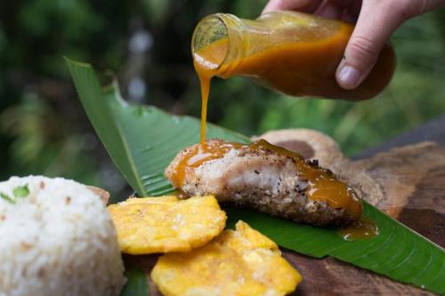 a person drizzling sauce on a plate of food at Casa Prana, Termales, Nuqui in Nuquí