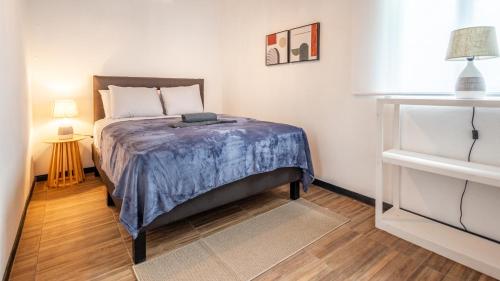 a bedroom with a bed with a blue blanket on it at BUDDA HOME in Tortuguero