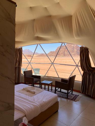 a bedroom with a bed and a large window at Diamond Wadi Rum Luxury Camp in Wadi Rum