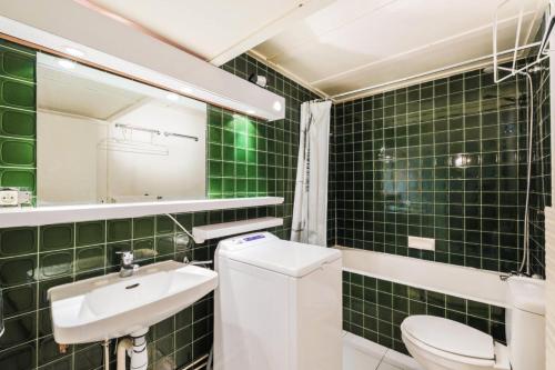 La salle de bains est pourvue de carrelage vert, de toilettes et d'un lavabo. dans l'établissement Résidence Aldébaran - maeva Home - Appartement 2 Pièces 6 Personnes - Budget MAE-3807, à Arâches-la-Frasse