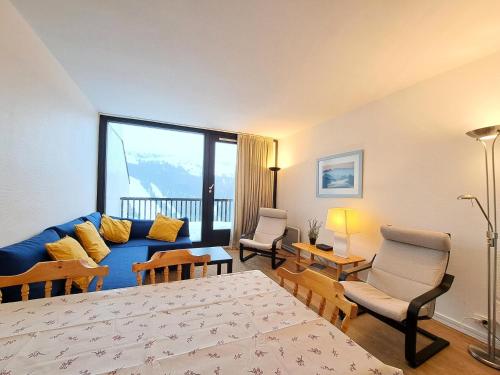 un salon avec un canapé bleu et des chaises dans l'établissement Résidence Capricorne - maeva Home - Appartement 2 Pièces 6 Personnes - Confort MAE-3832, à Arâches-la-Frasse