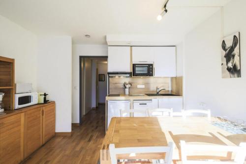une cuisine et une salle à manger avec une table et des chaises en bois dans l'établissement Résidence Castor - maeva Home - Appartement 2 Pièces 6 Personnes - Confort MAE-3847, à Arâches-la-Frasse