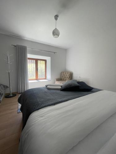 a white bedroom with a large bed with a window at Paja Guesthouse - Camping in Bogë