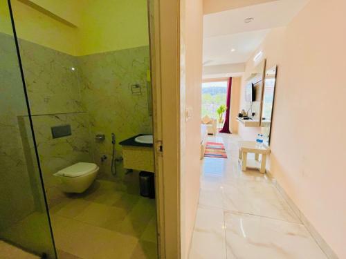 a bathroom with a toilet and a glass shower at Hotel The Tirath View in Haridwār