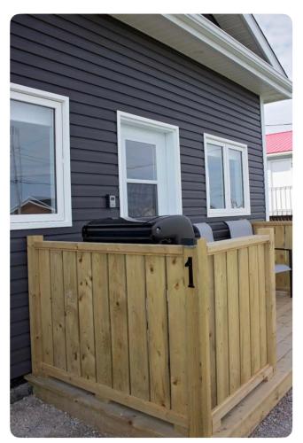 a black house with a wooden fence in front of it at Gros Morne Coastal Suites in Rocky Harbour