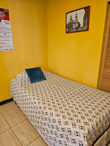 a bed in a room with a yellow wall at Hostal Pucara Molina in Molina