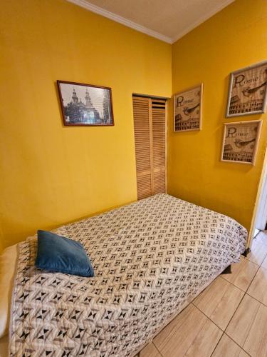 a bedroom with a bed in a yellow wall at Hostal Pucara Molina in Molina