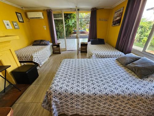 two beds in a room with yellow walls at Hostal Pucara Molina in Molina