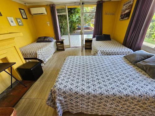 two beds in a room with yellow walls at Hostal Pucara Molina in Molina