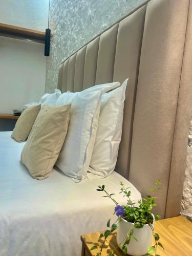 a bed with white pillows and a plant on a table at Hotel Aatu - Adults Only in Peratallada