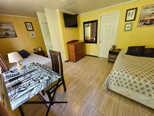 a bedroom with a bed and a table and a bed and yellow walls at Hostal Pucara Molina in Molina
