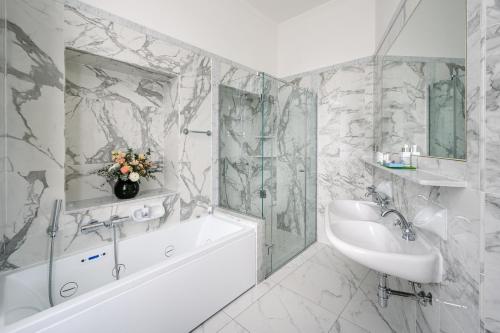 ein weißes Badezimmer mit einem Waschbecken, einer Badewanne und einem Badetubermott in der Unterkunft Grand Hotel Villa Serbelloni - 150 Years of Grandeur in Bellagio
