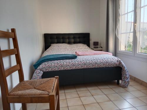 um quarto com uma cama, uma cadeira e uma janela em Les Hortensias em Challans