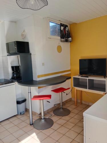 une cuisine avec une table et deux tabourets rouges dans l'établissement Les Hortensias, à Challans