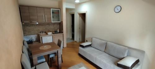 ein Wohnzimmer mit einem Sofa, einem Tisch und einer Uhr in der Unterkunft Apartman Miletić 4 in Zlatibor