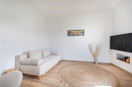 a white living room with a couch and a tv at Appartement Blanqui - Welkeys in La Seyne-sur-Mer