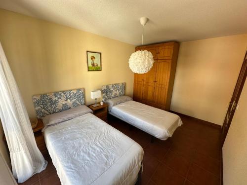 sypialnia z 2 łóżkami i żyrandolem w obiekcie PLAYA DE SAN VICENTE DE LA BARQUERA w mieście San Vicente de la Barquera
