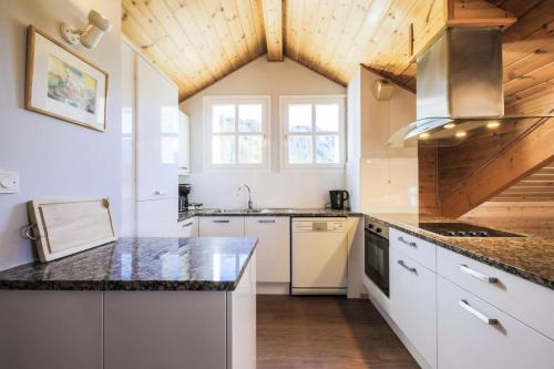 une cuisine avec des armoires blanches et un plafond en bois dans l'établissement Résidence Le Château de Crans - maeva Home - Appartement 5 pièces 10 personnes avec sauna privé - Prestige MAE-4441, à Flaine