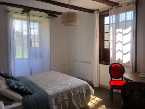 a bedroom with a bed and a red chair at LA CONQUISE in Conques-en-Rouergue