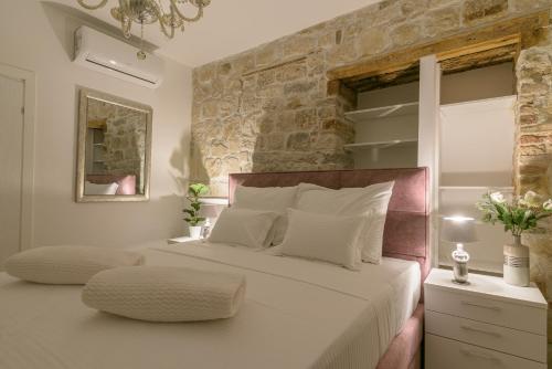 sypialnia z dużym białym łóżkiem i kamienną ścianą w obiekcie Sobe Bartul Trogir w Trogirze