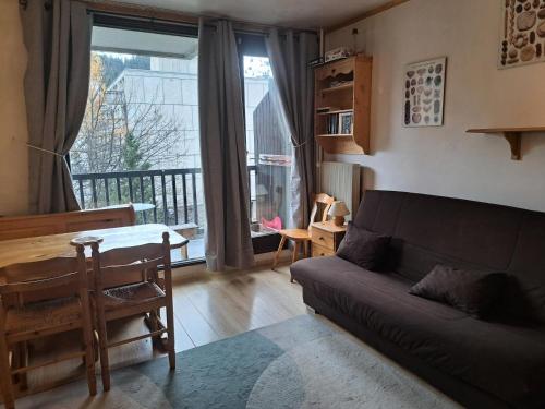 un salon avec un canapé, une table et une fenêtre dans l'établissement Résidence Véga - maeva Home - Studio 4 Personnes - Budget MAE-4467, à Arâches-la-Frasse