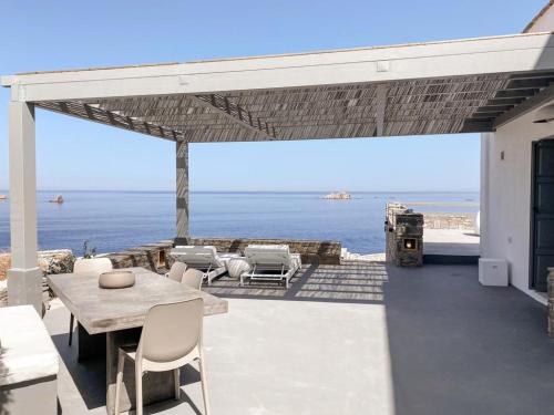 a patio with a table and chairs and the ocean at Cliff Villa in Sarakíniko