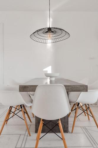 a dining table with two white chairs and aendant light at Cliff Villa in Sarakíniko