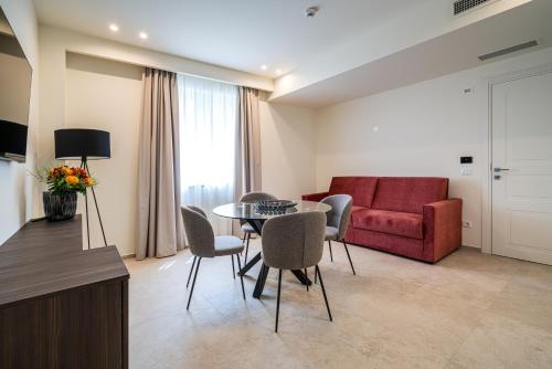 a living room with a table and chairs and a red couch at I Due Mori - Luxury Rooms in Giardini Naxos
