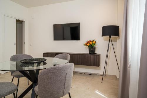 a dining room with a table and chairs and a television at I Due Mori - Luxury Rooms in Giardini Naxos