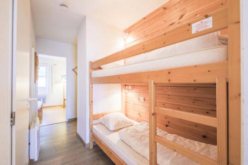 - une chambre avec des lits superposés et un mur en bois dans l'établissement Résidence Le Château de Crans - maeva Home - Appartement 2 Pièces 6 Personnes - Sélection MAE-4725, à Flaine
