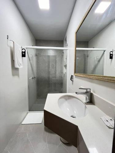 a white bathroom with a sink and a shower at Regente Hotel in Pato Branco