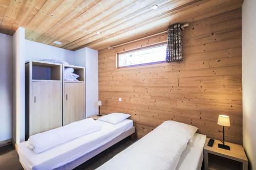 - 2 lits dans une chambre avec un mur en bois dans l'établissement Résidence Refuge du Golf - maeva Home - Appartement 4 Pièces 8 Personnes - Prestige MAE-5505, à Arâches-la-Frasse